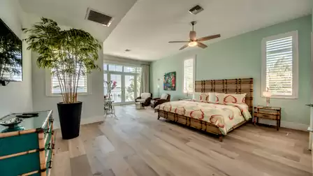 Tropical-inspired bedroom with a bamboo bed, warm colors, and terrace access.