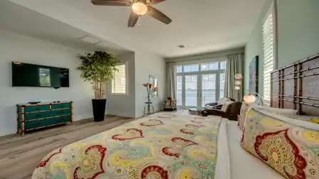 Spacious bedroom with tropical flair, wooden furniture, and direct balcony access overlooking the water.