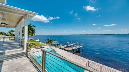Breathtaking balcony view of the infinity pool, boat dock, and the vast blue river.
