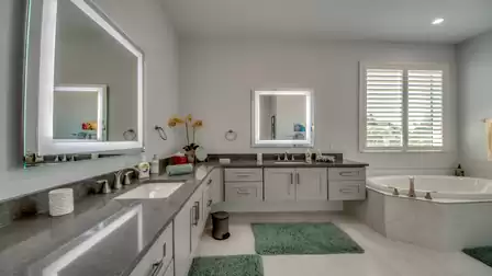 Luxurious bathroom with double sinks, illuminated mirrors, and a whirlpool bathtub.