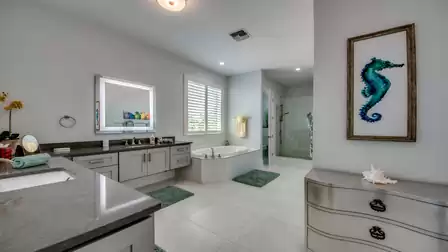 Modern bathroom with double sinks, illuminated mirror, and bathtub.