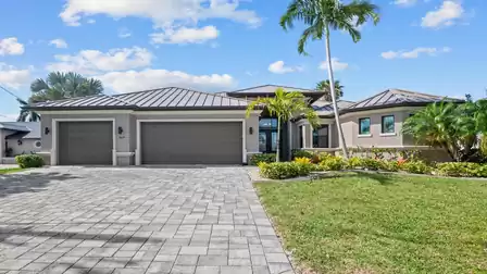 Modern Villa Elvenar in Cape Coral with a well-maintained front yard and spacious driveway.