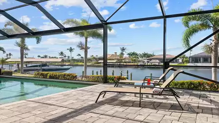 Sun loungers by the pool area of Villa Elvenar overlooking the canal with a luxury motorboat in the background.