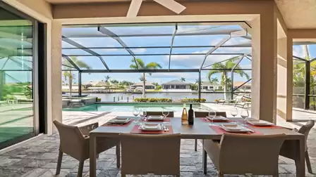 Elegant outdoor dining area of Villa Elvenar with a view of the pool and canal.