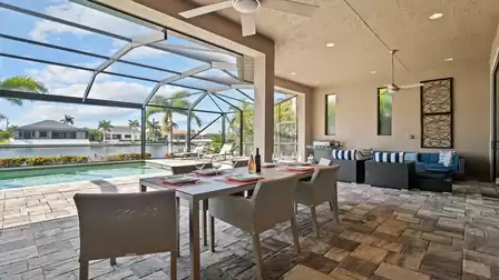Covered terrace of Villa Elvenar with dining area, lounge, and view of the waterway.