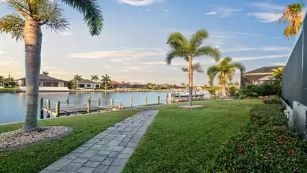 Garden path with palm trees leading to the dock of Villa Elvenar, picturesque view of the canal.