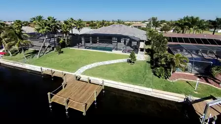 Aerial view of the vacation home with pool area, garden, and boat dock in a quiet residential area.