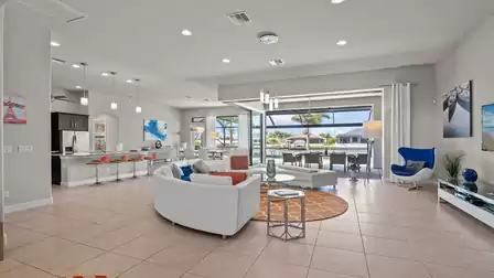 Stylishly furnished living room with an open kitchen, modern design, and a view of the pool area.
