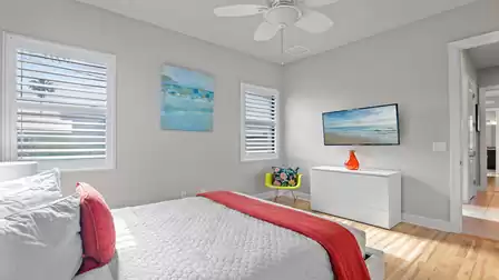 Bright bedroom with stylish decor, TV, and large windows with an outdoor view.