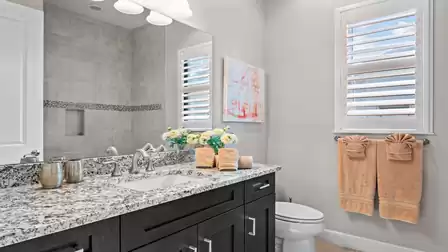 Stylish bathroom with granite vanity, mirror, and decorative towels.