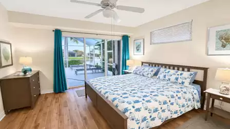 Bedroom with king bed, teal curtains and sliding doors to terrace and canal