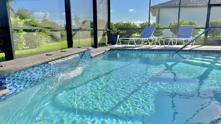 Pool with waterfall and sun loungers for relaxing moments.