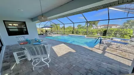 Covered patio with dining table and pool view.