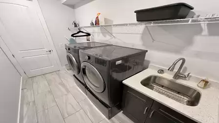 Laundry room with modern washing machines, dryer, and sink