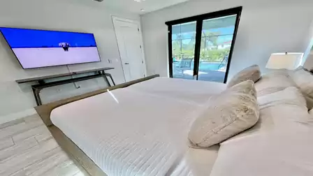 Bedroom with king-size bed, TV, and pool view