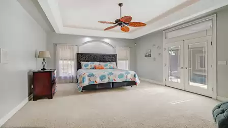 Spacious master bedroom with decorative headboard, colorful bedspread, and direct terrace access.