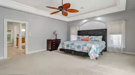 Luxurious master bedroom with high ceilings, ceiling fan, and stylish interior.
