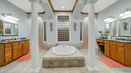 Luxurious master bathroom with Roman bathtub, dual vanities, and elegant columns.