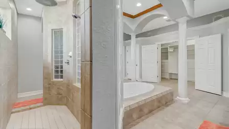 Walk-in shower with glass blocks and view of the master bathroom with spacious walk-in closet.