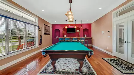 Stylish billiard room with hardwood floors, bar area, and direct access to the patio.