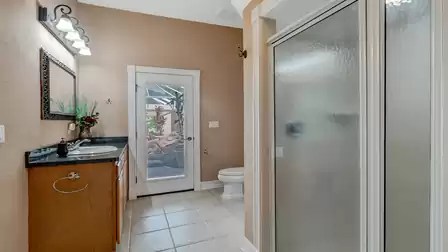 Modern bathroom with a shower, vanity, and direct access to the pool terrace. Light tiles and soft lighting create a pleasant atmosphere.