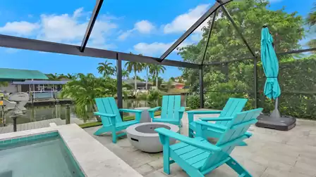 Seating area at Villa Kamala in Cape Coral with a spa, fire pit, and canal view.