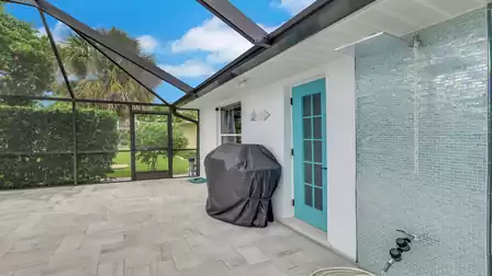 Screened patio at Villa Kamala in Cape Coral with an outdoor shower and barbecue grill.