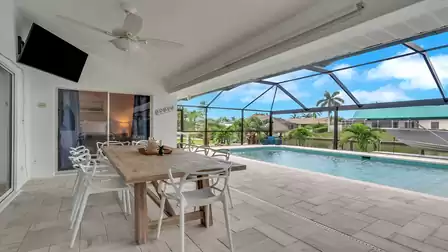 Covered outdoor dining area at Villa Kamala in Cape Coral with pool and canal view.