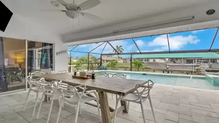 Covered outdoor dining area at Villa Kamala in Cape Coral with pool, spa, and canal view.