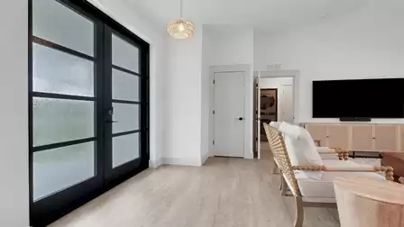 Modern living room with seating area, TV, and spacious entrance.