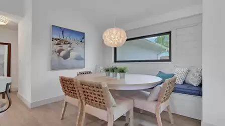 Modern dining area with a round dining table, built-in bench seating, and a large window.