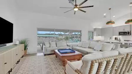 Open-plan living area with comfortable sofas, a modern kitchen, and views of the pool patio.