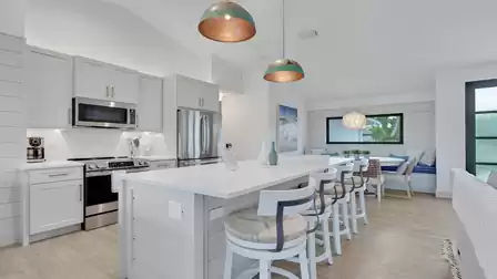 Modern kitchen with a spacious island, bar stools, and an open dining area.