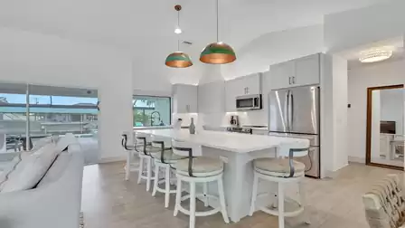 Bright kitchen with a large island, bar stools, and direct access to the pool patio.