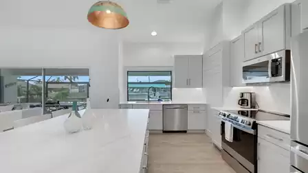 Modern kitchen with a spacious island, light cabinetry, and views of the pool patio.