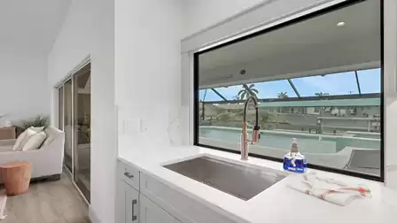 Modern kitchen with a large sink and panoramic window overlooking the private pool.