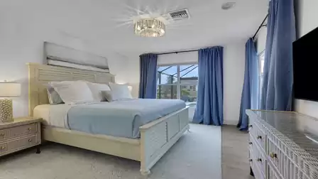 Bright bedroom with a king-size bed, large windows, and a view of the pool.