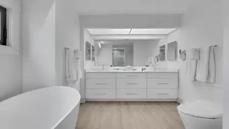 Modern bathroom with a freestanding bathtub, double vanity, and large mirror.