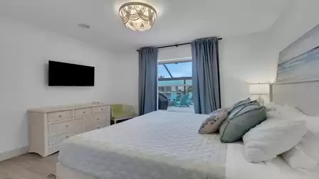 Modern bedroom with a queen-size bed, smart TV, and direct access to the pool patio.