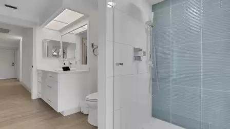 Modern bathroom with a walk-in shower, vanity, and large mirror.