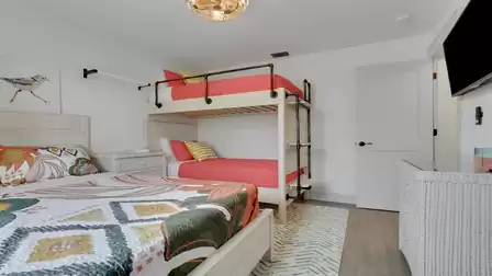 Family bedroom with a queen-size bed, bunk bed, smart TV, and bright modern interior.