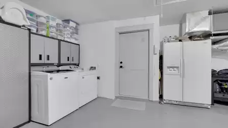 Garage with a washer, dryer, extra refrigerator, and practical storage space.