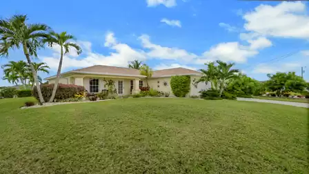 Exterior view of Villa Nevena in Cape Coral with a tropical garden and well-maintained lawn.