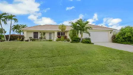 Exterior view of Villa Nevena in Cape Coral with palm trees and a well-maintained front garden.