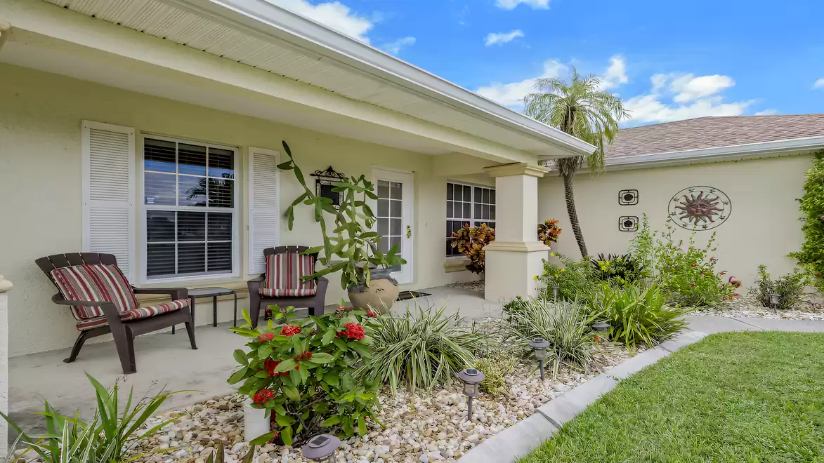 Covered front entrance with a seating area and beautifully landscaped garden.