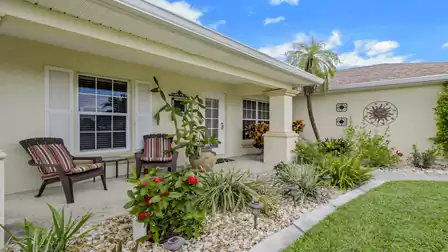 Covered front entrance with a seating area and beautifully landscaped garden.