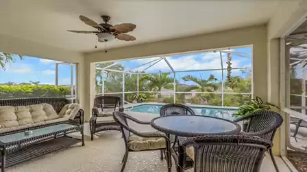 Covered patio with a dining area, lounge seating, and views of the pool.