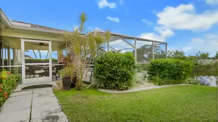 Well-maintained garden with a screened pool patio and canal view.