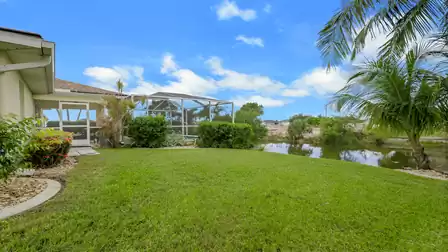 Spacious garden with a lawn, pool patio, and canal view.