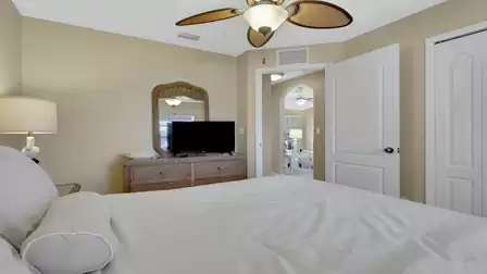 Cozy bedroom with a TV, rattan furniture, and access to the living area.